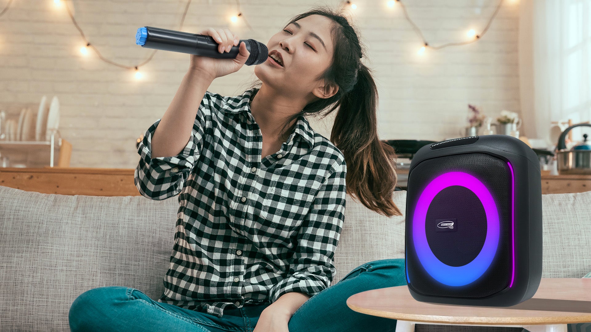 Young woman sitting on the lounge singing with a karaoke speaker