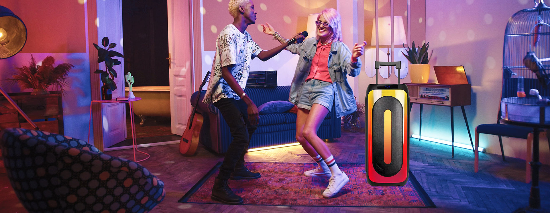 Young man and lady dancing in the living room with a party speaker and lights